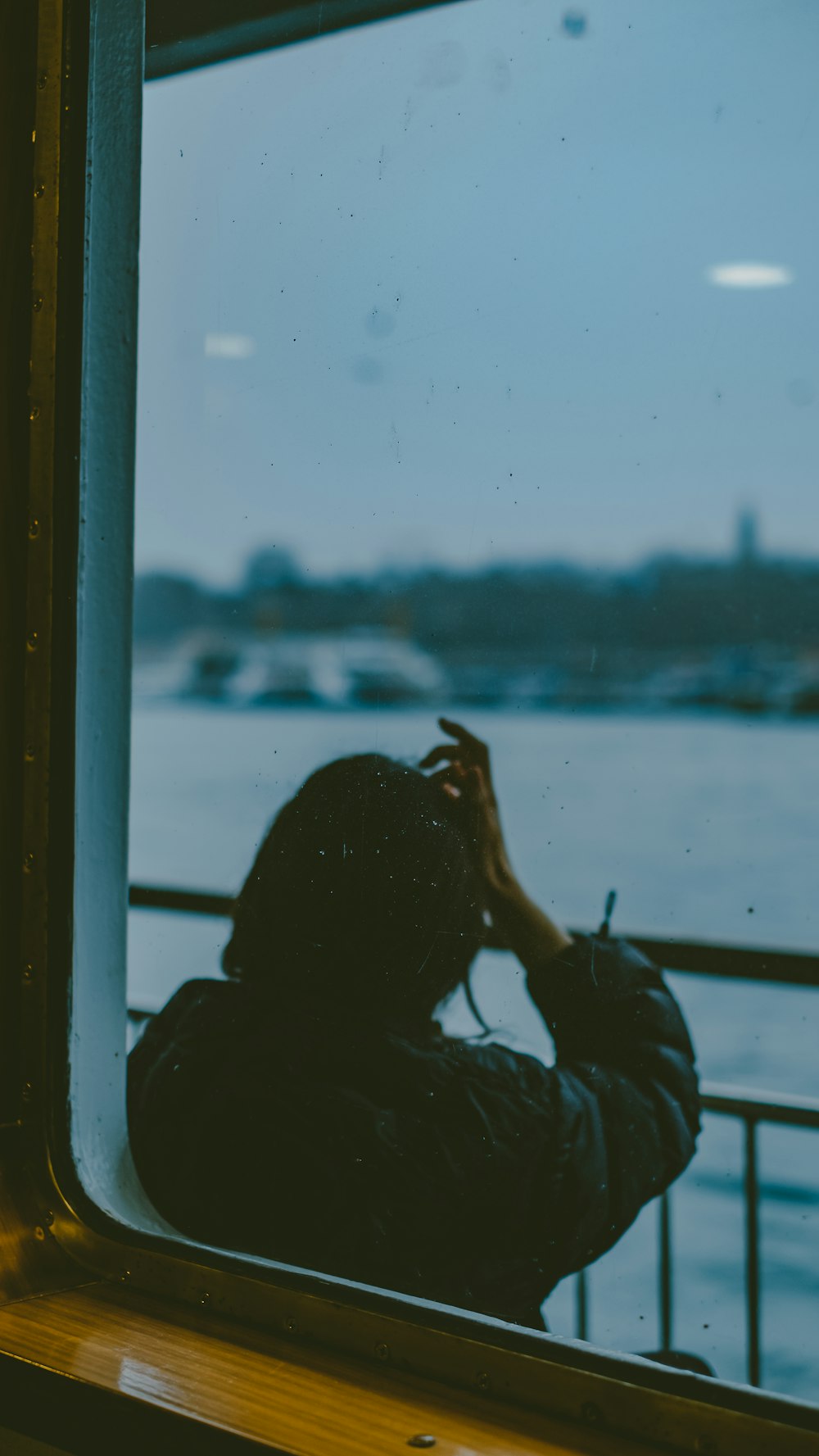 a person looking out a window at a body of water
