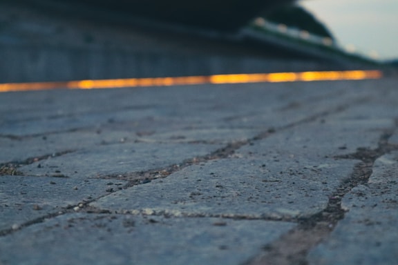 A close-up image of textured paving stones illuminated softly against a dark background.