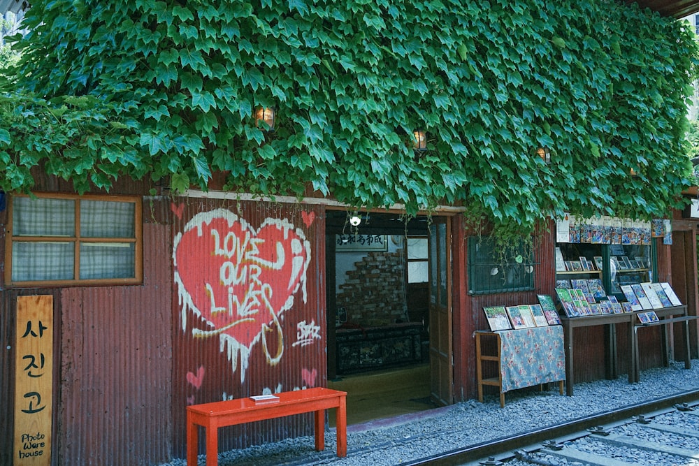 a red bench sitting in front of a building covered in vines