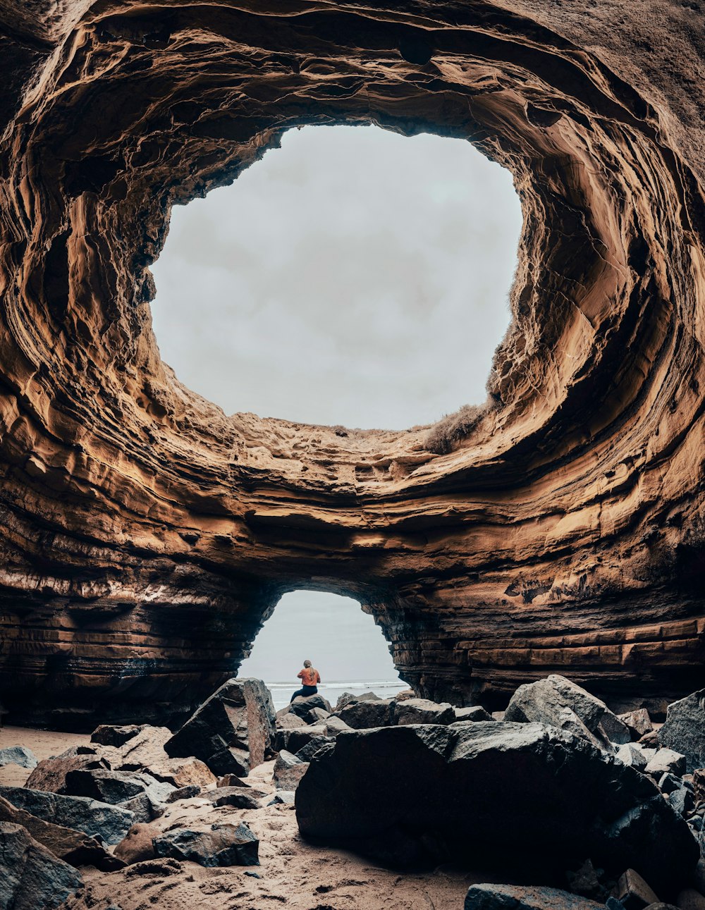 a person sitting in a cave on a rocky beach
