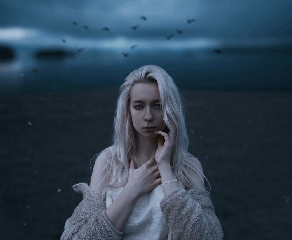 a woman with long white hair standing in a field