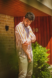 A friendly handyman wearing a green shirt, holding tools, standing in front of a house.
