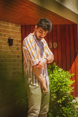 A friendly handyman wearing a green shirt, holding tools, standing in front of a house.