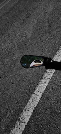 Close-up of the dual mirrors on the training vehicle reflecting the road.