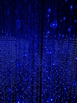 A mesmerizing scene filled with cascading strings of blue LED lights resembling a starry sky. The arrangement creates an immersive, almost infinite depth, captivating the viewer's gaze. It's unclear whether it's a physical installation or a digital simulation.