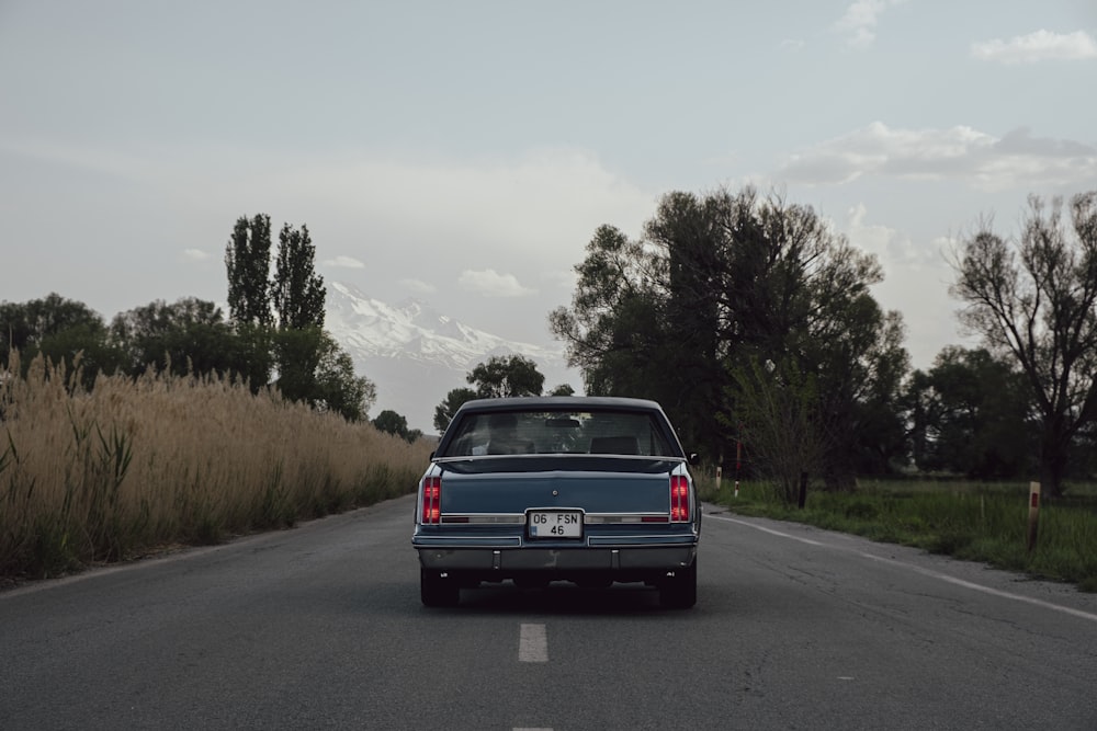 a car is driving down the road with a mountain in the background