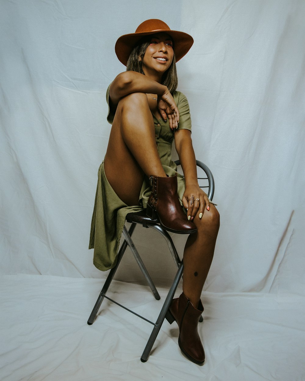 a woman sitting on a chair wearing a hat