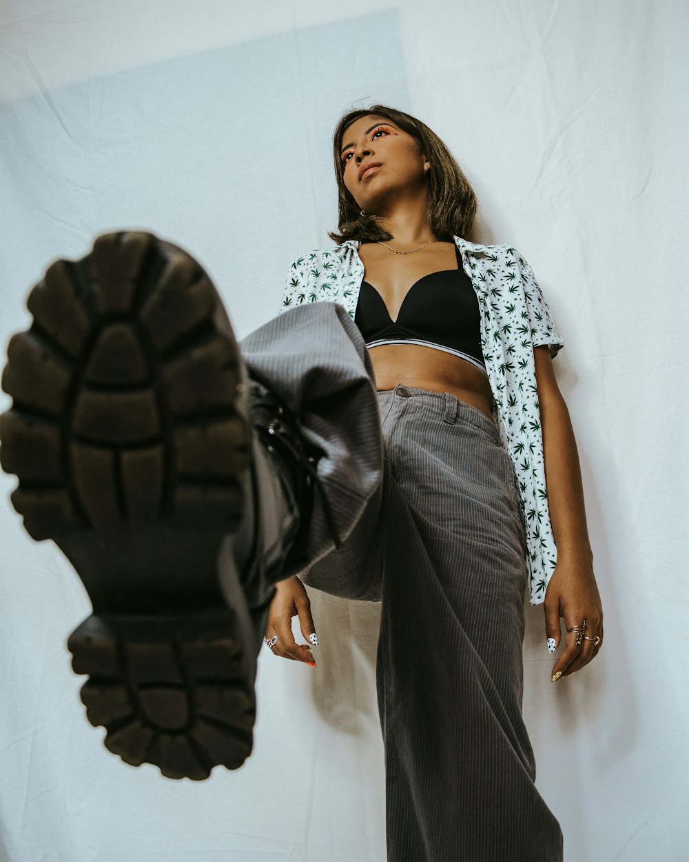 a woman leaning against a wall with a pair of shoes