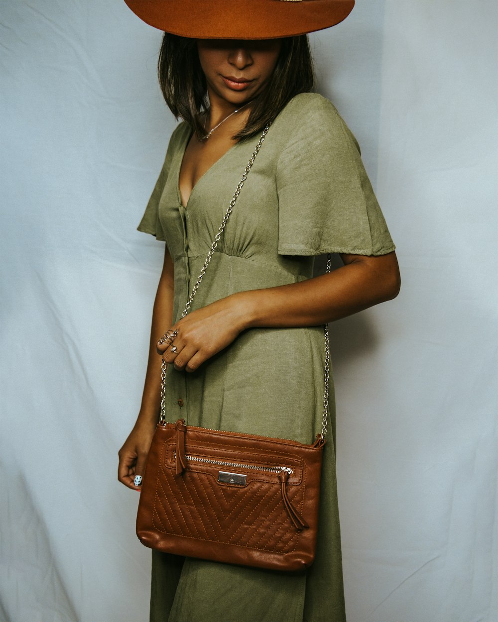 a woman wearing a brown hat and holding a brown purse