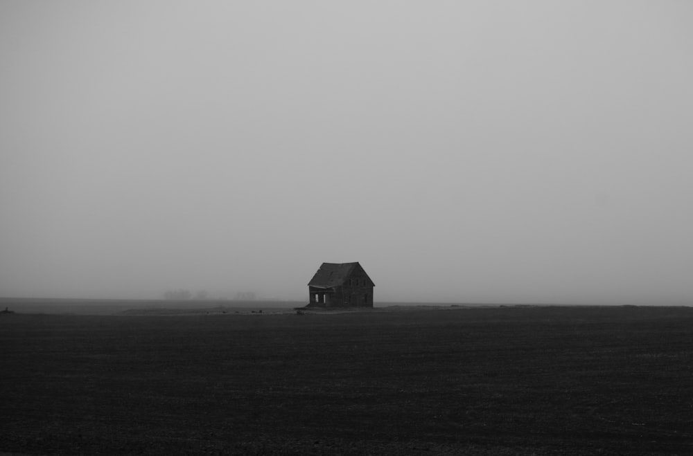 a black and white photo of a house in the middle of a field