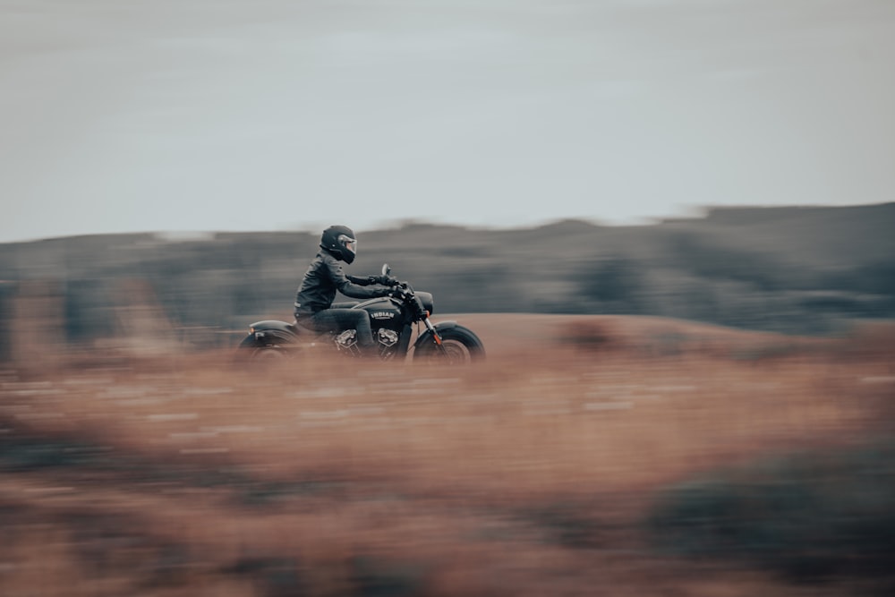 a man riding a motorcycle through a field