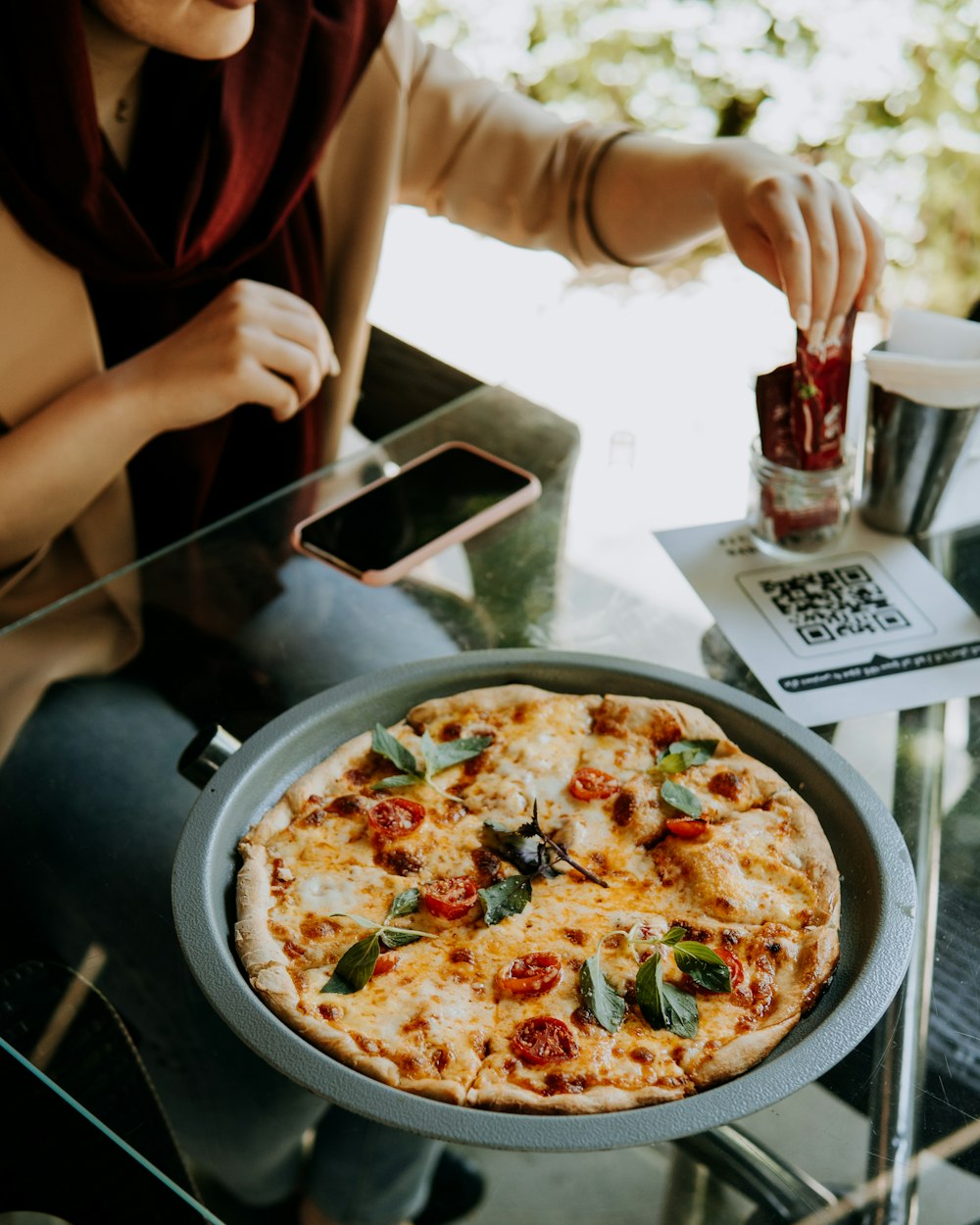 a woman sitting at a table with a pizza in front of her