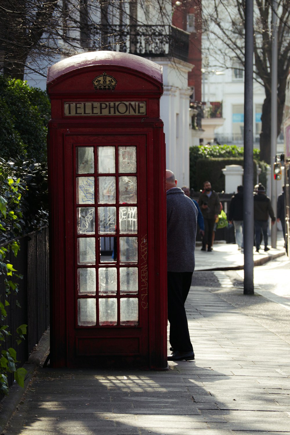 a man standing next to a red phone booth