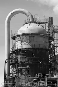 a black and white photo of a factory with pipes