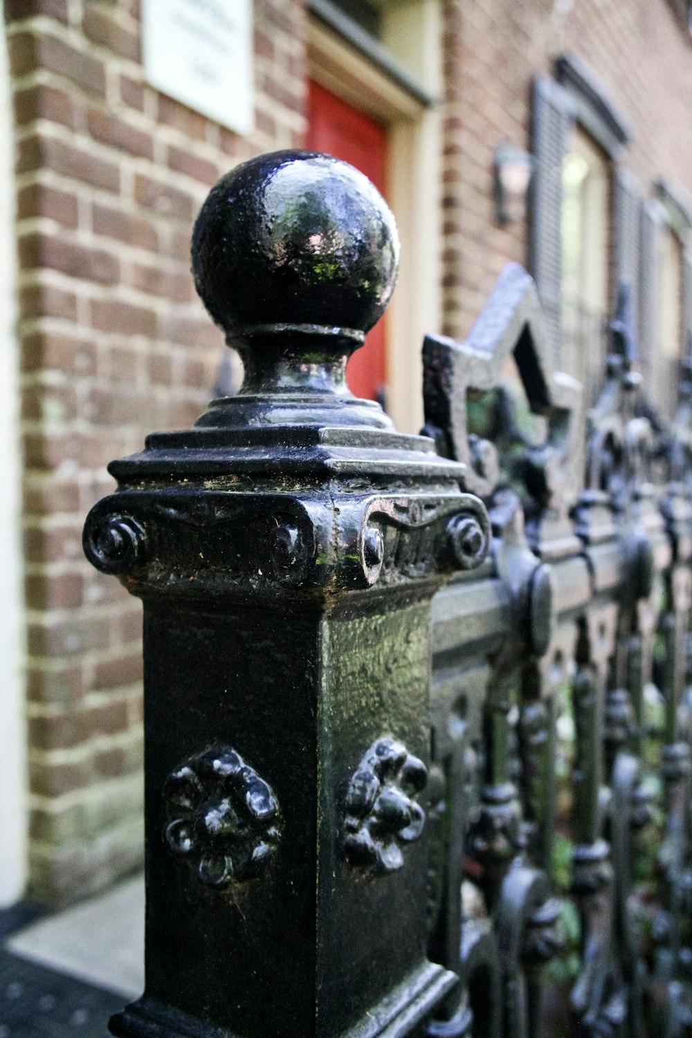 a close up of a fence with a brick building in the background