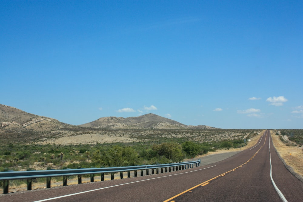 a highway with mountains in the background and a blue sky