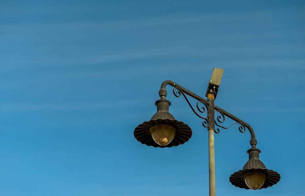 two street lights on a pole against a blue sky