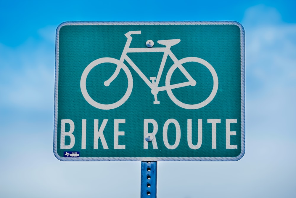 a green street sign that says bike route