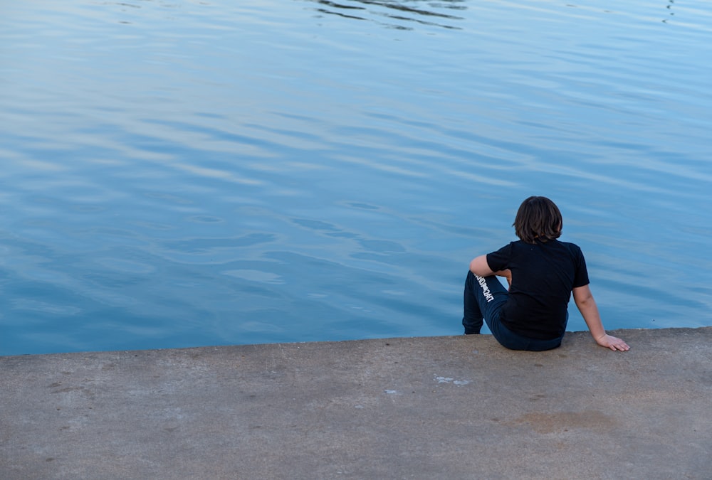 Una persona sentada en el borde de un cuerpo de agua