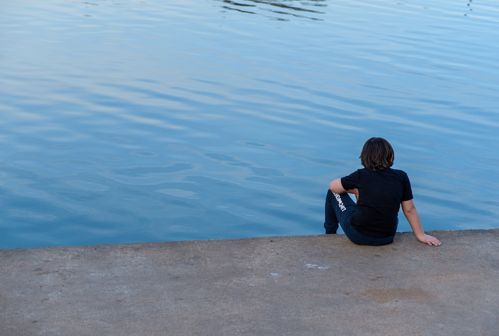 a person sitting on the edge of a body of water