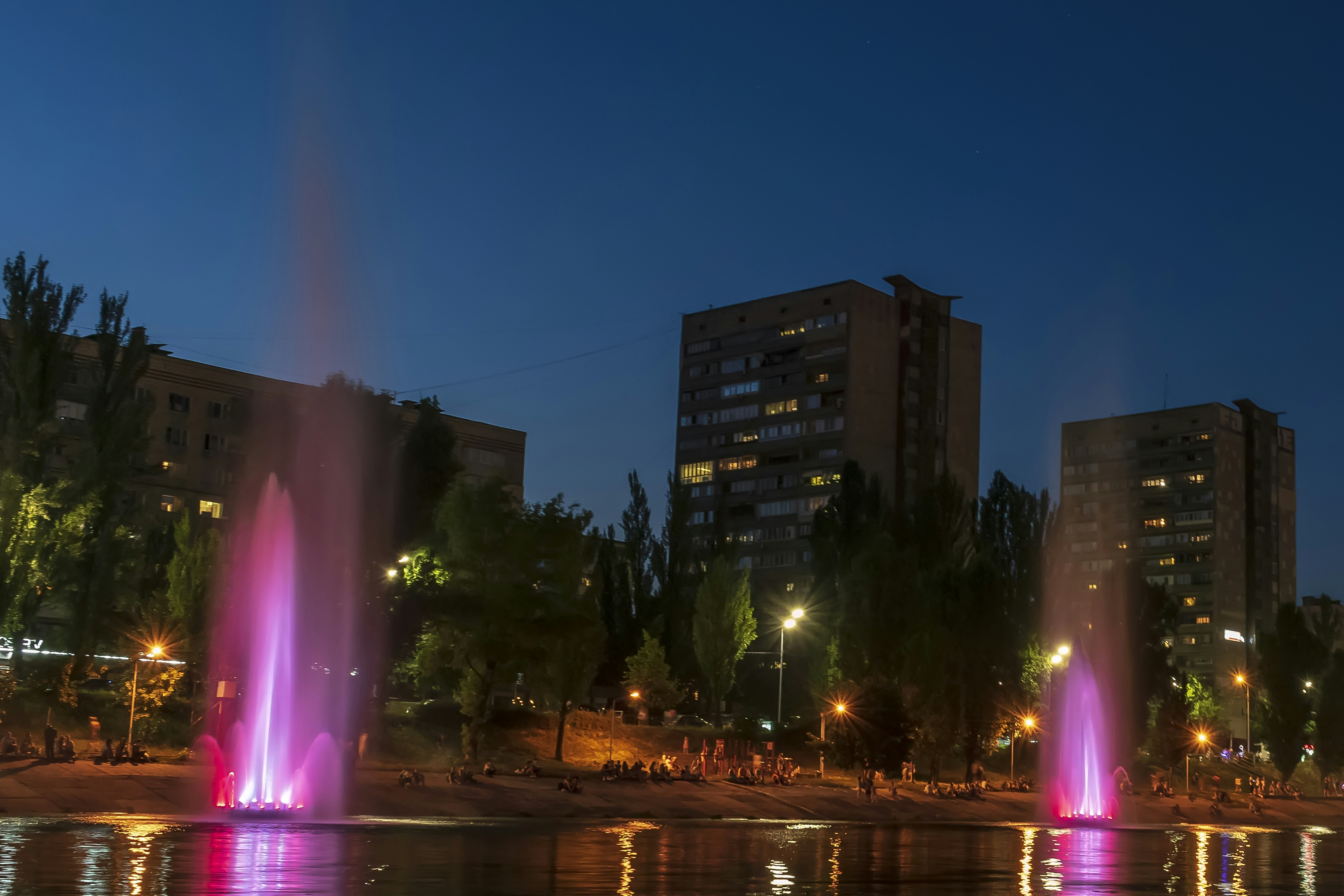 a group of water fountains in front of a city at night