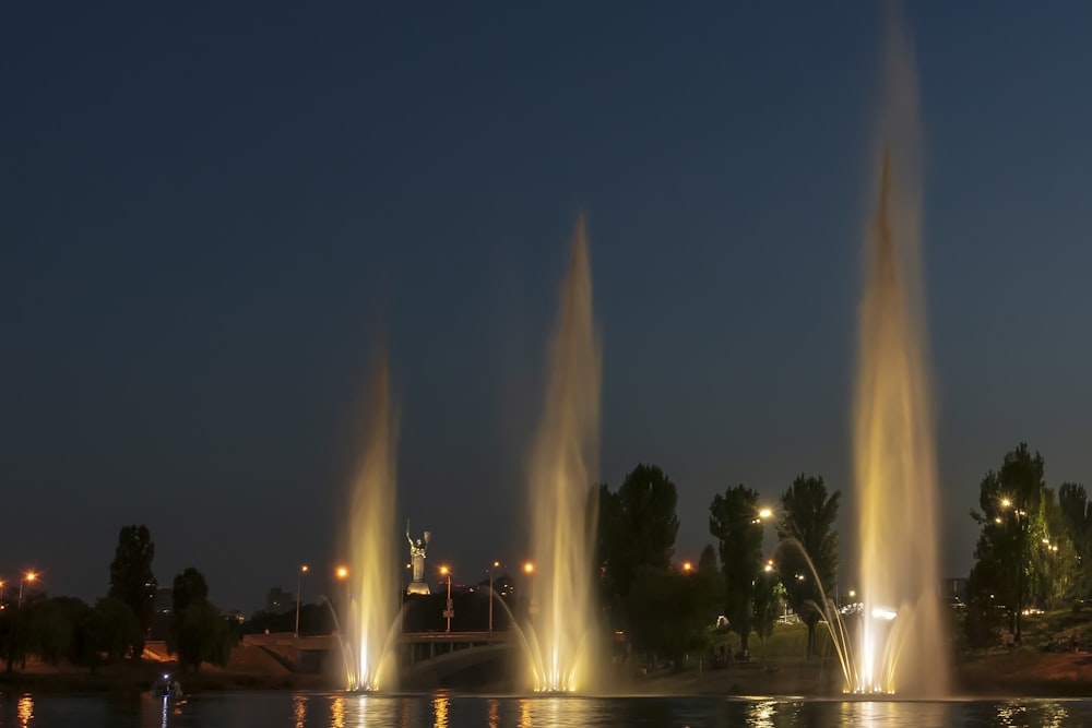 a group of fountains in the water at night