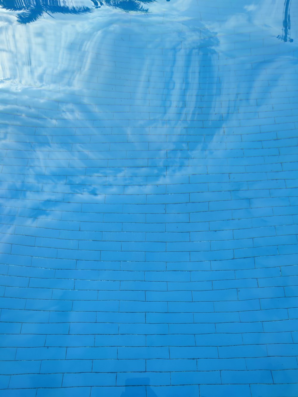 a blue tiled swimming pool with a sky background