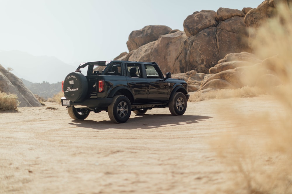 a black truck driving down a dirt road