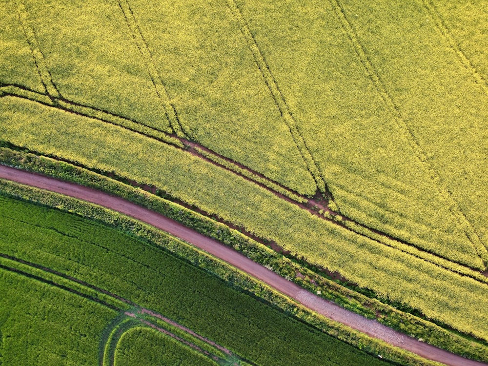 an aerial view of a road in the middle of a green field