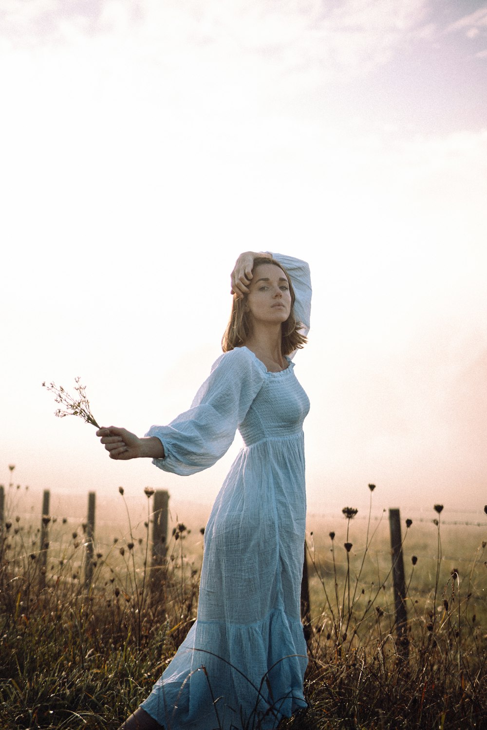 a woman in a white dress is holding a flower