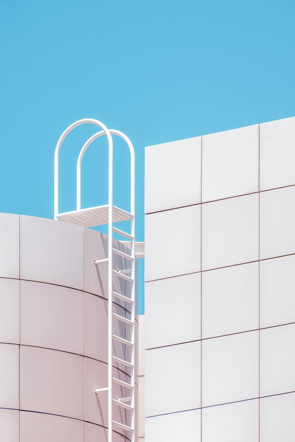 a ladder leaning against a white wall with a blue sky in the background