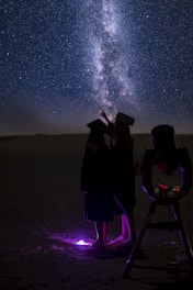 a couple of people standing next to each other under a sky filled with stars