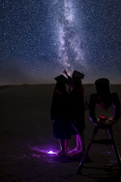 a couple of people standing next to each other under a sky filled with stars