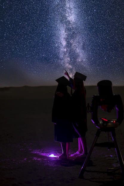 a couple of people standing next to each other under a sky filled with stars