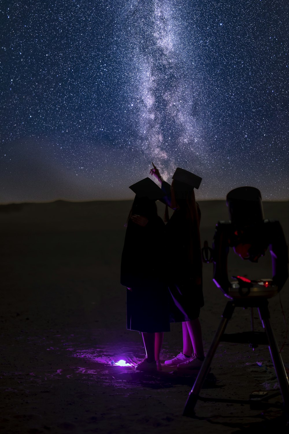 a couple of people standing next to each other under a sky filled with stars