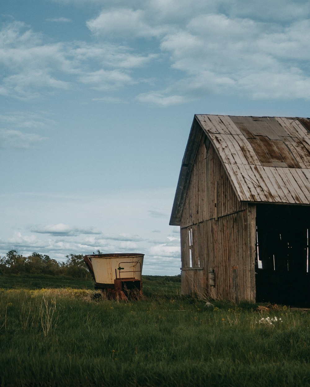 an old barn and a wooden wagon in a field