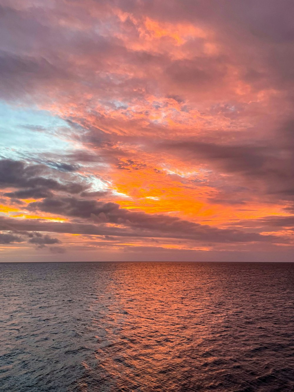 a sunset over a body of water with a boat in the distance