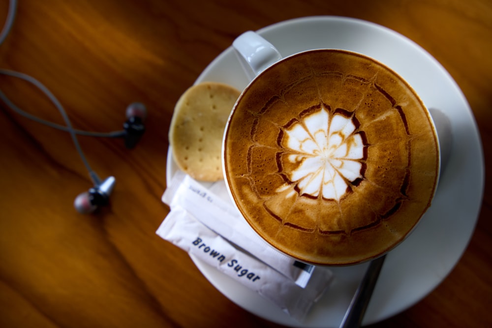 a cappuccino on a plate next to a pair of headphones