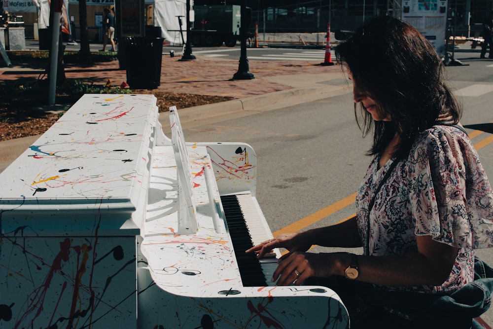 a woman sitting on the ground playing a piano