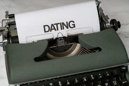 A vintage typewriter with a sheet of paper showing the words 'Save the Date' in cursive.