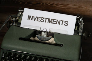 a close up of a typewriter with a paper that reads investments
