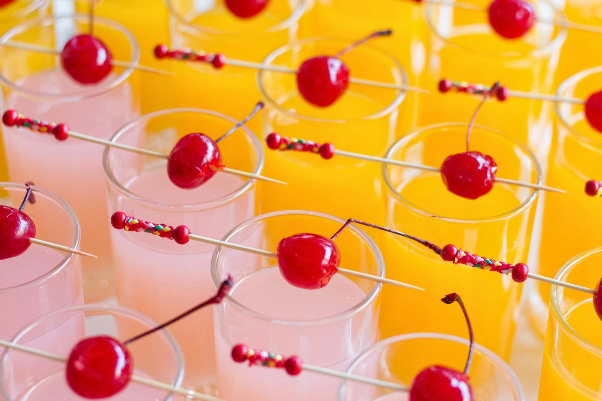 a row of glasses filled with drinks and cherries