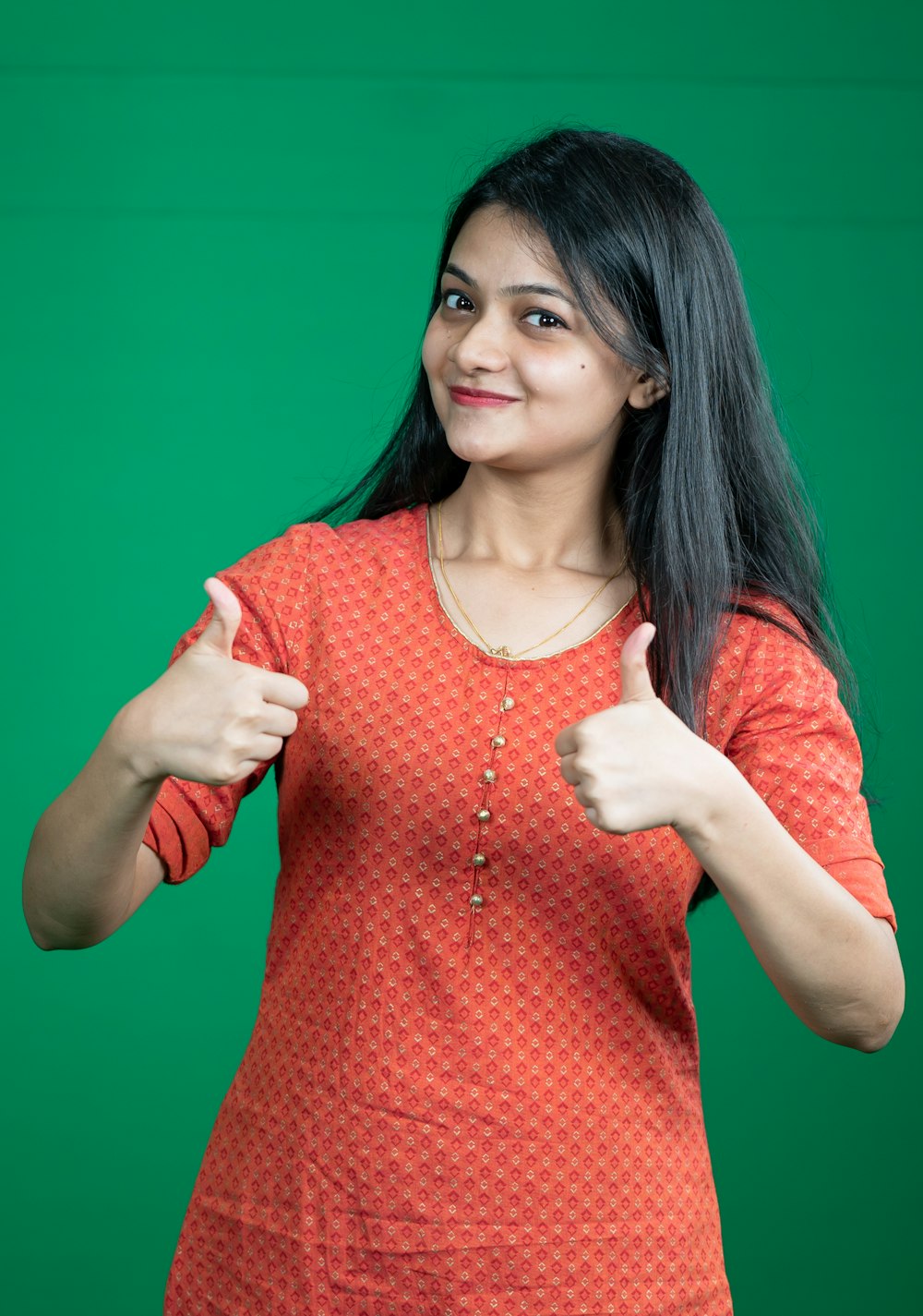 a woman giving a thumbs up sign in front of a green background