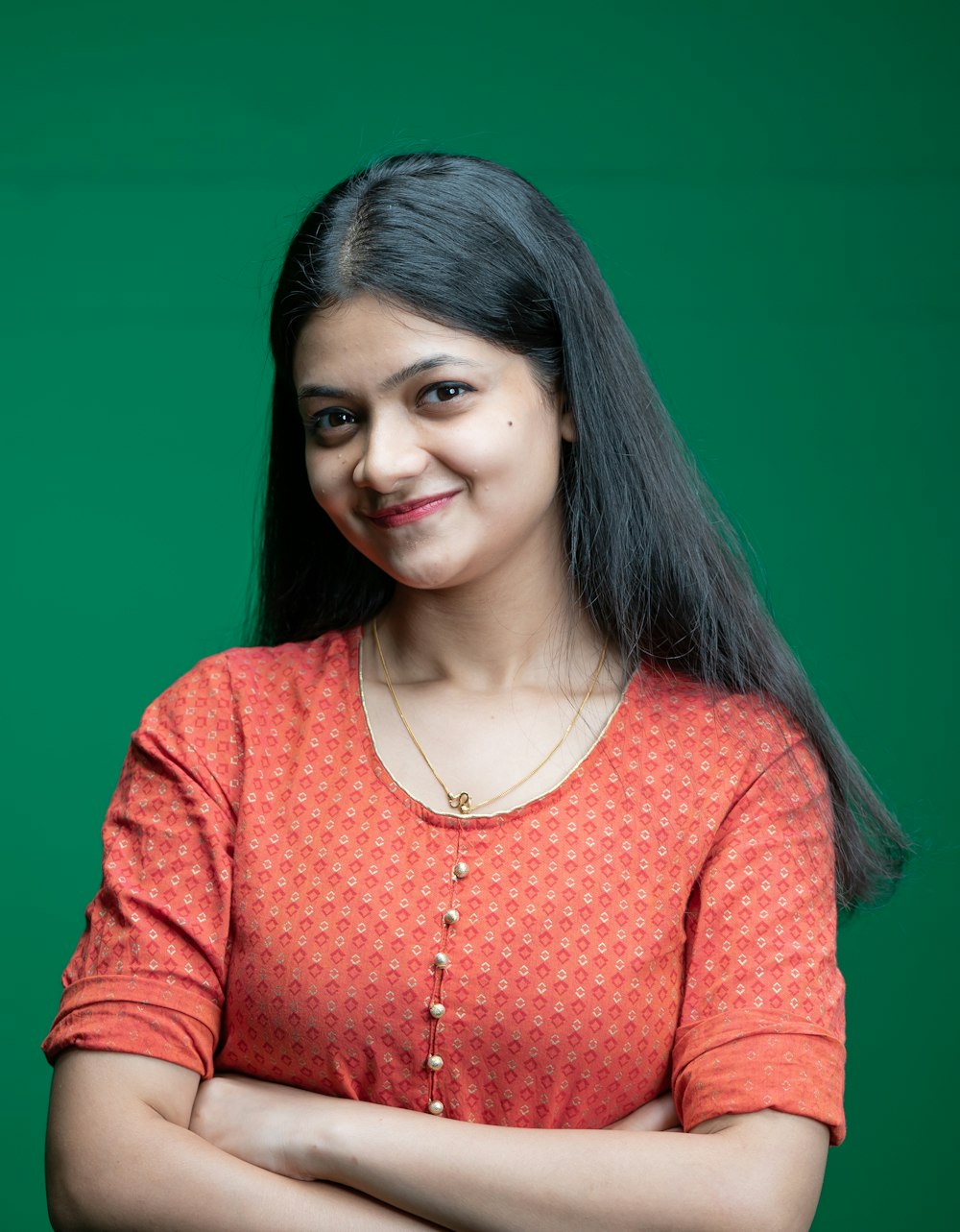 a woman standing with her arms crossed in front of a green background