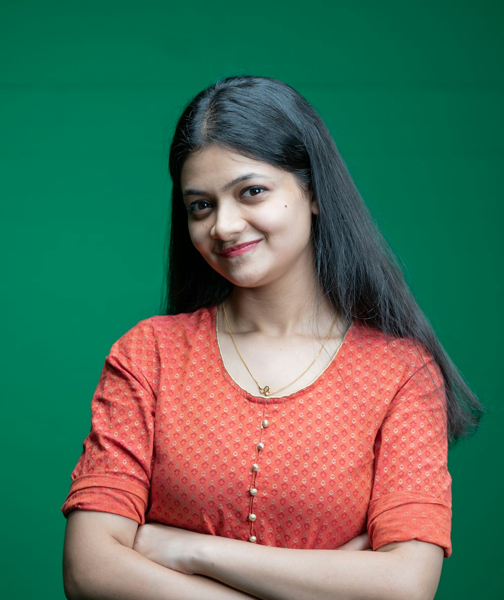 a woman standing with her arms crossed in front of a green background