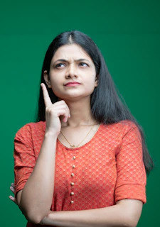 a woman in an orange top is holding her finger up