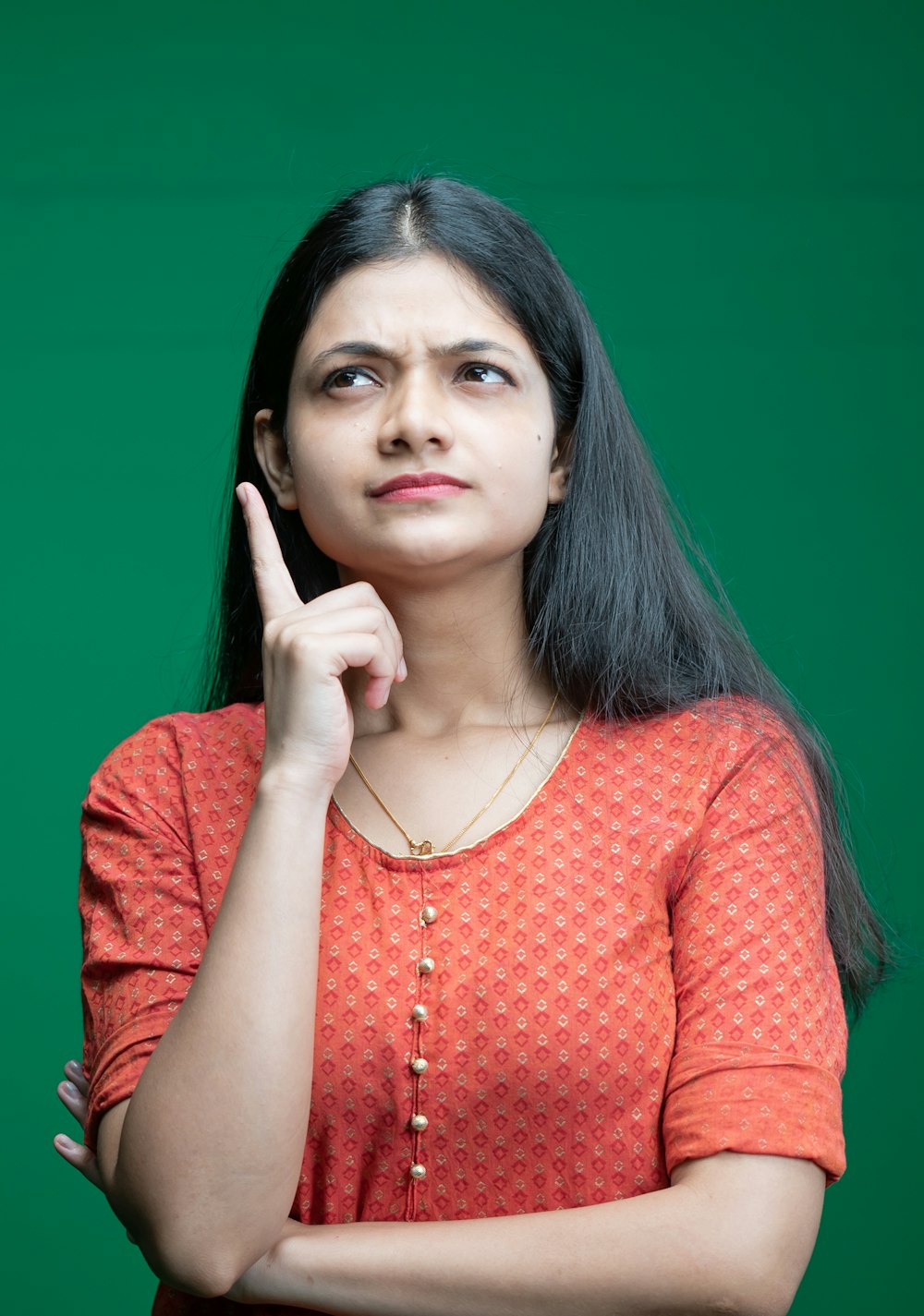 a woman in an orange top is holding her finger up