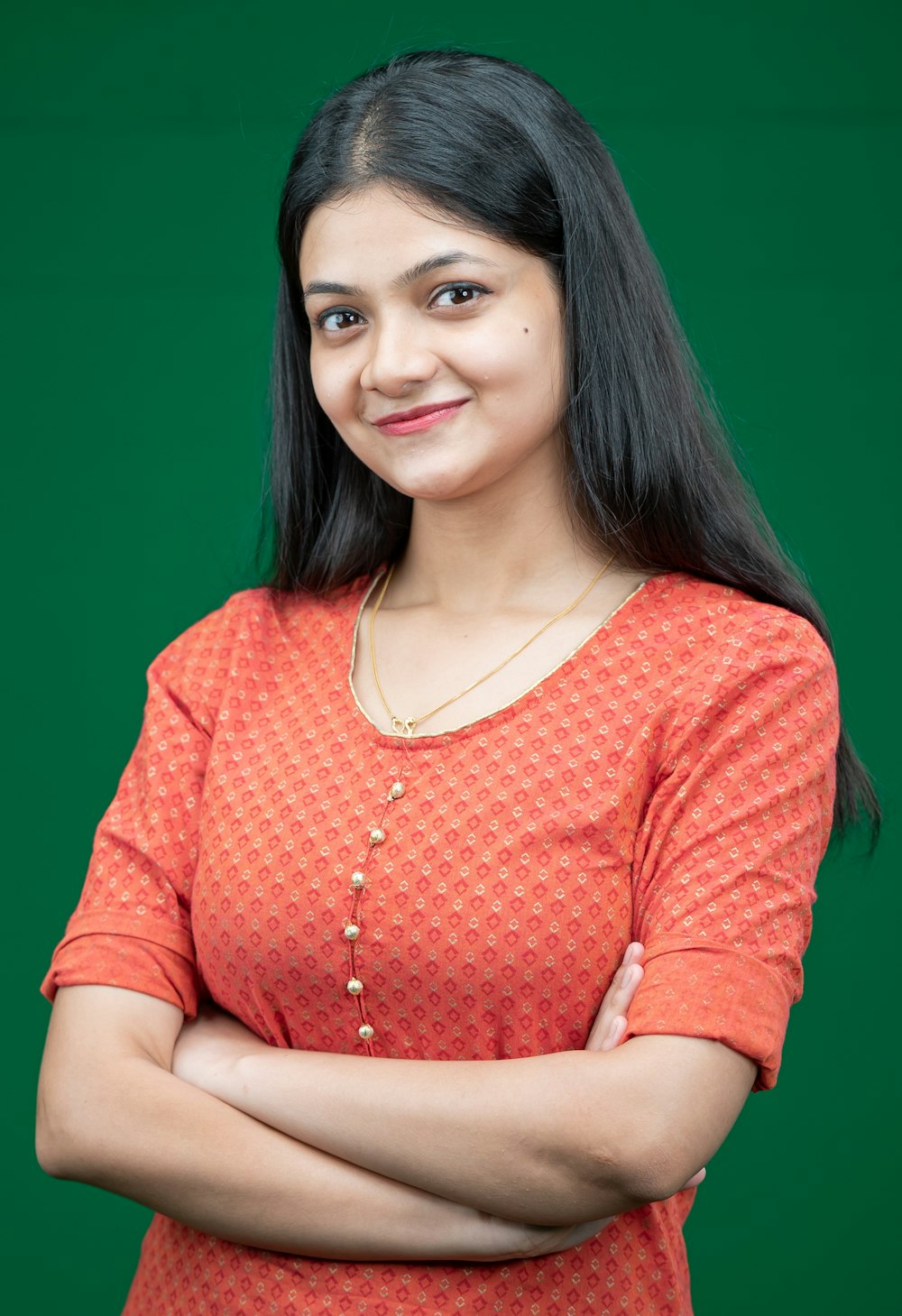 a woman with her arms crossed standing in front of a green background