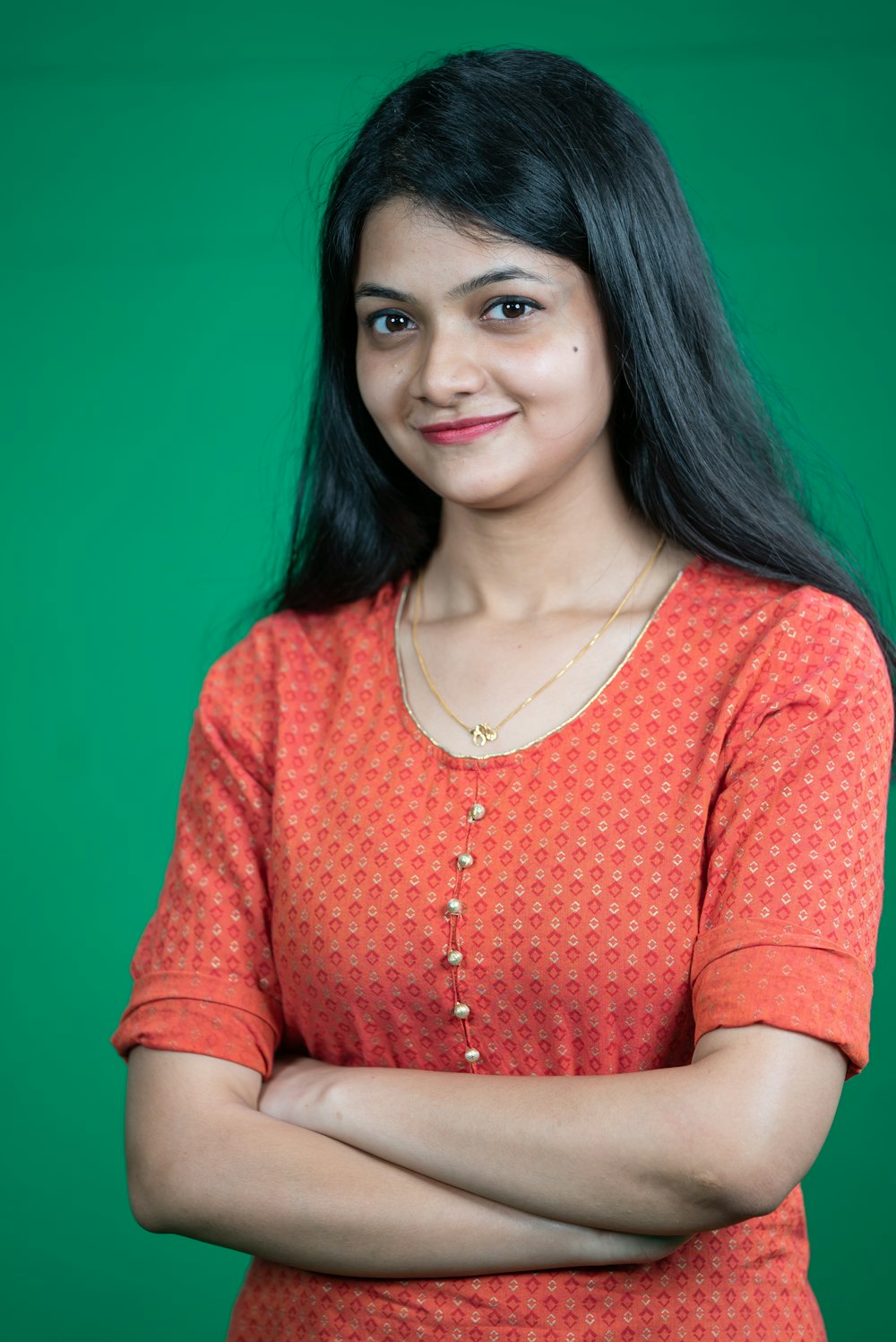 a woman standing with her arms crossed in front of a green background