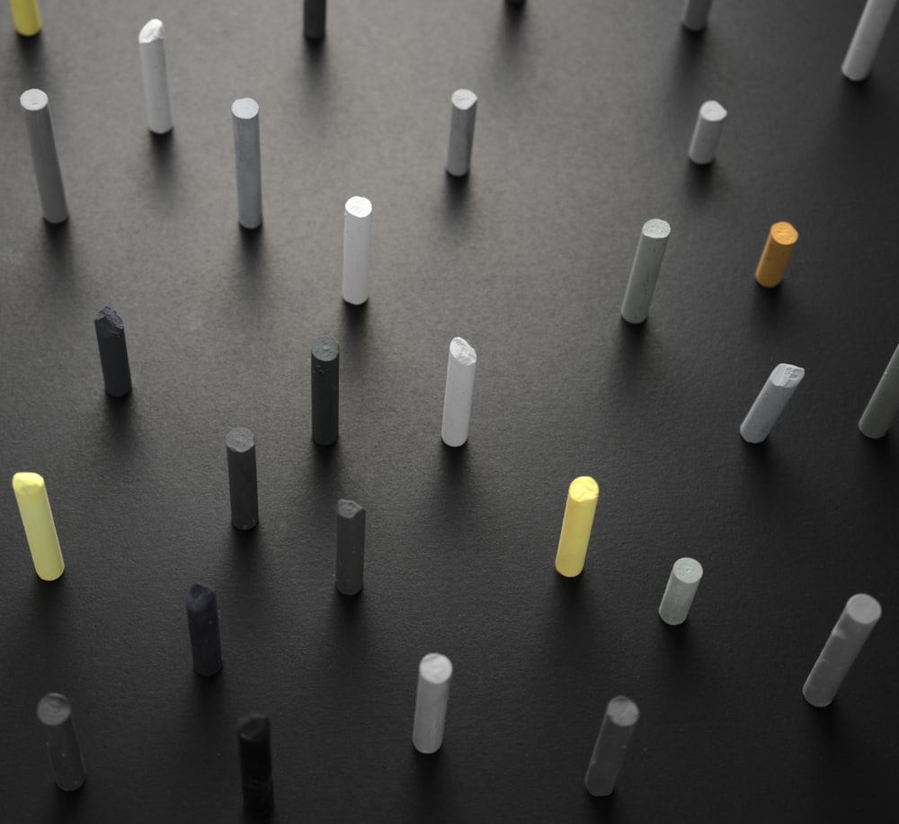 a group of white and yellow poles on a black surface